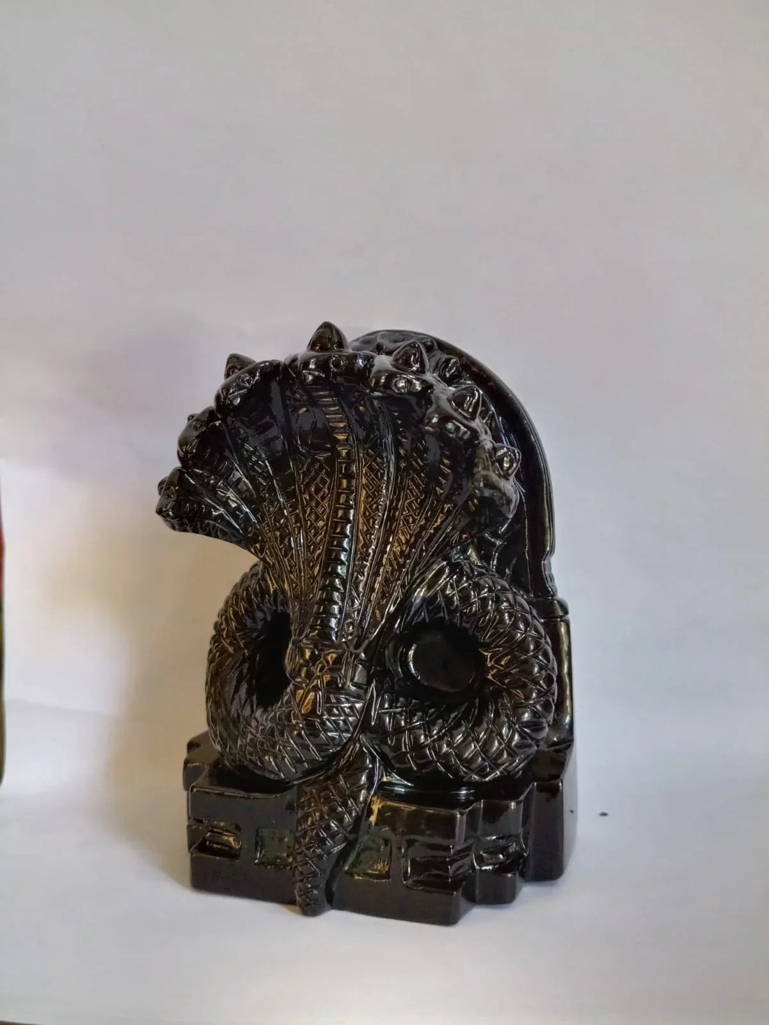 Black carved statue of a multi-headed cobra snake on a white background