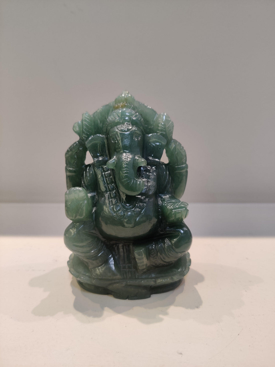 Green jade statue of Hindu deity Ganesha on a plain white surface