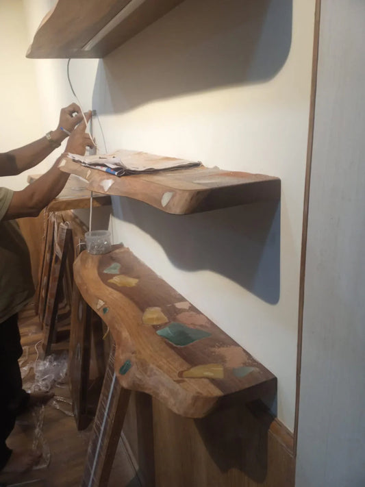 Man installing rustic wooden shelves with colorful inlays on beige wall inside a room