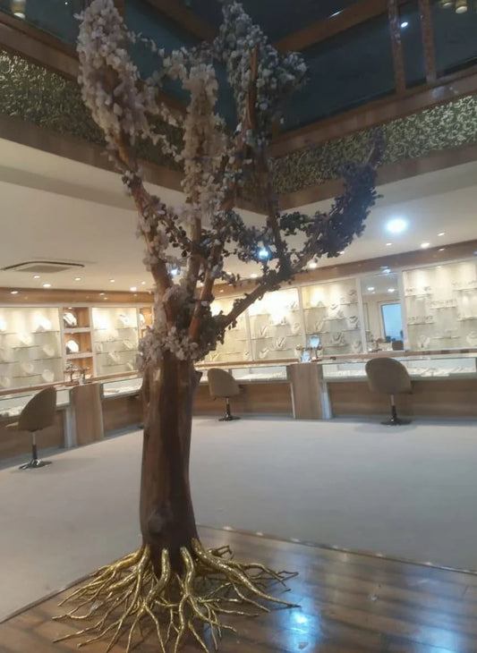 Indoor decorative tree with white blossoms and golden roots inside jewelry store showroom